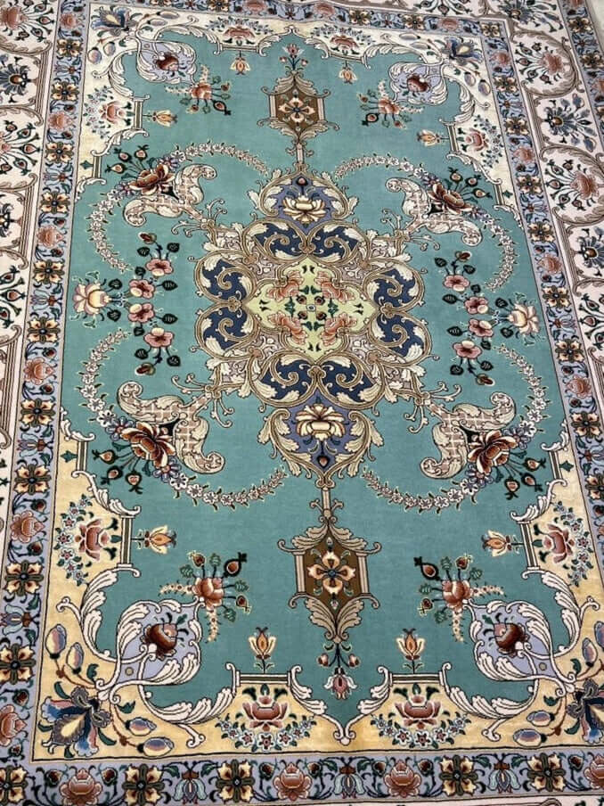 "Luxury Isfahan carpet in aqua, gold, and navy hues, featuring intricate floral patterns and silk accents."